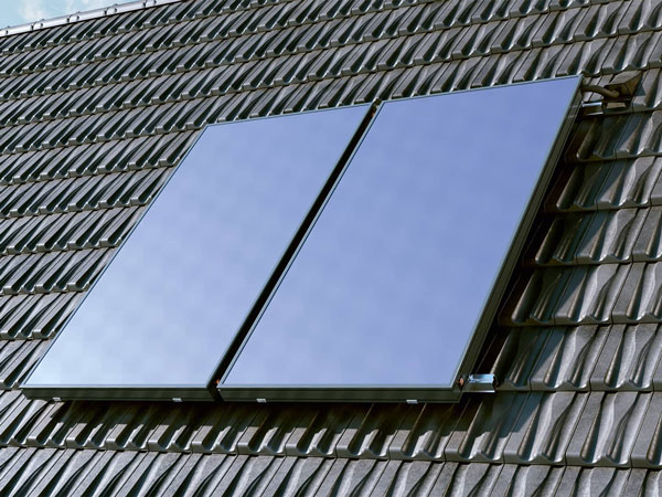 Zwei rechteckige Solarkollektoren auf einem Dach mit dunklen Dachziegeln.